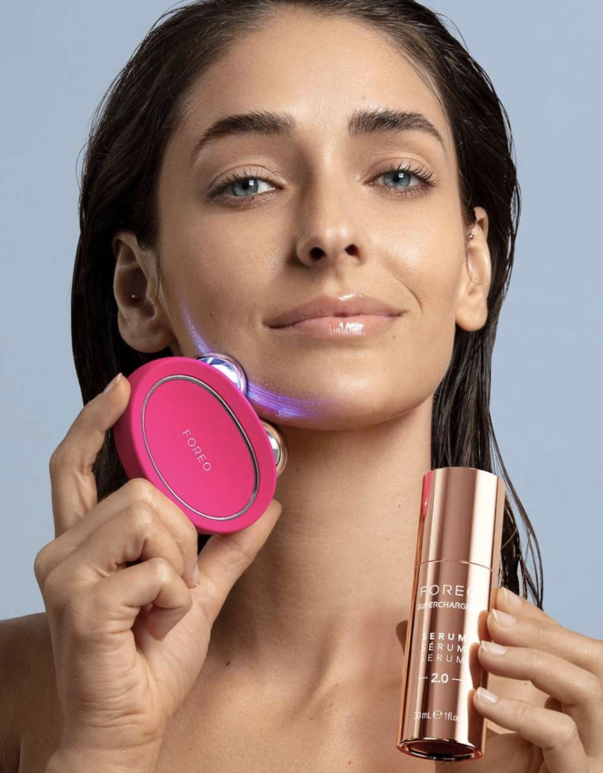 Modelo usando FOREO BEAR 2 en la mandíbula, con el sérum SUPERCHARGED en la otra mano